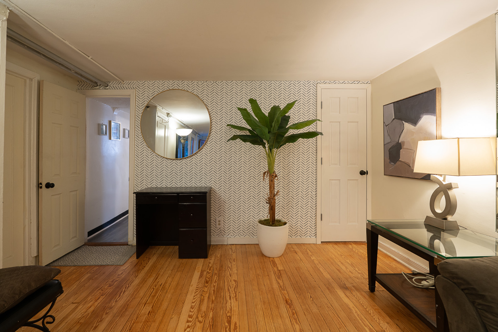 Welcoming foyer with a round mirror, console table, and tall palm plant